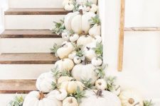 a staircase decorated with lots of white pumpkins, greenery and boho macrame for chic fall decor