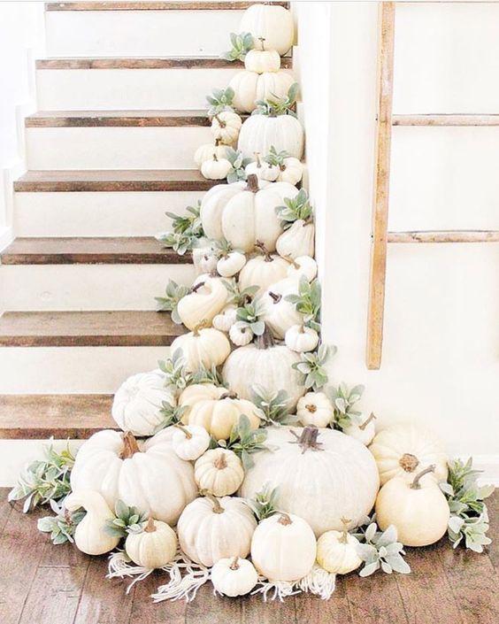 a staircase decorated with lots of white pumpkins, greenery and boho macrame for chic fall decor