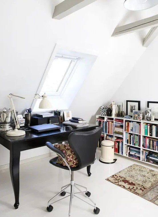 a stylish Scandinavian home office with wooden beams, a vintage black desk, a black leather chair, a large bookshelf, some rugs and pillows