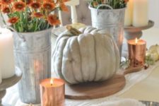 a stylish fall centerpiece of white pumpkins and a large heirloom one, orange blooms and candles