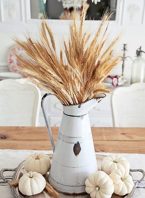 Une élégante pièce maîtresse d'automne de ferme avec une cruche en métal avec du blé et des citrouilles blanches sur un plateau en argent Une élégante pièce maîtresse d'automne de ferme avec une cruche en métal avec du blé et des citrouilles blanches sur un plateau en argent