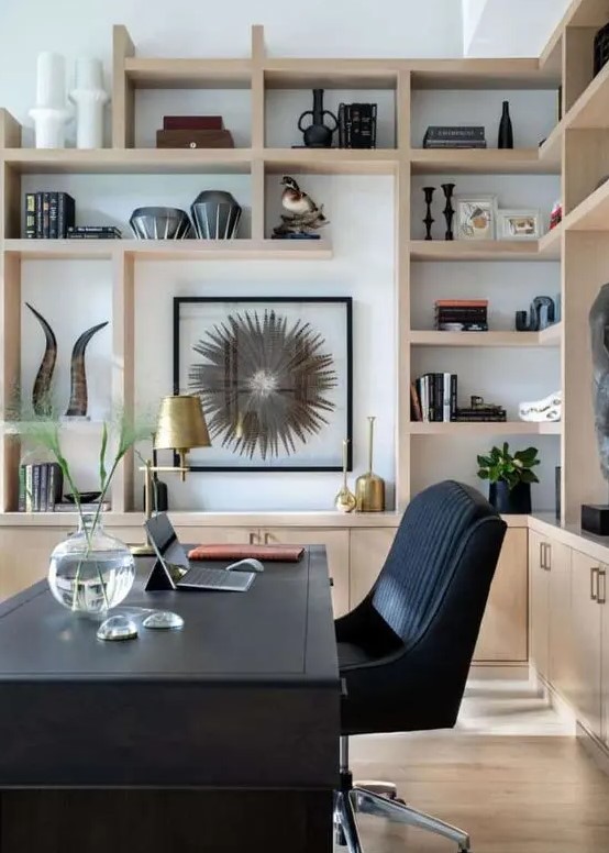 a stylish home office with a black desk and a chair, light-stained cabinets and shelves, gilded touches and artwork