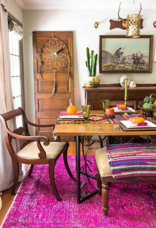 a super colorful boho dining room with a dream catcher, elegant wooden furniture, potted cacti and colorful textiles