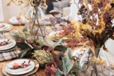 a super natural fall tablescape with plaid placemats, berries, fruits, foliage and dried herbs and blooms in vases