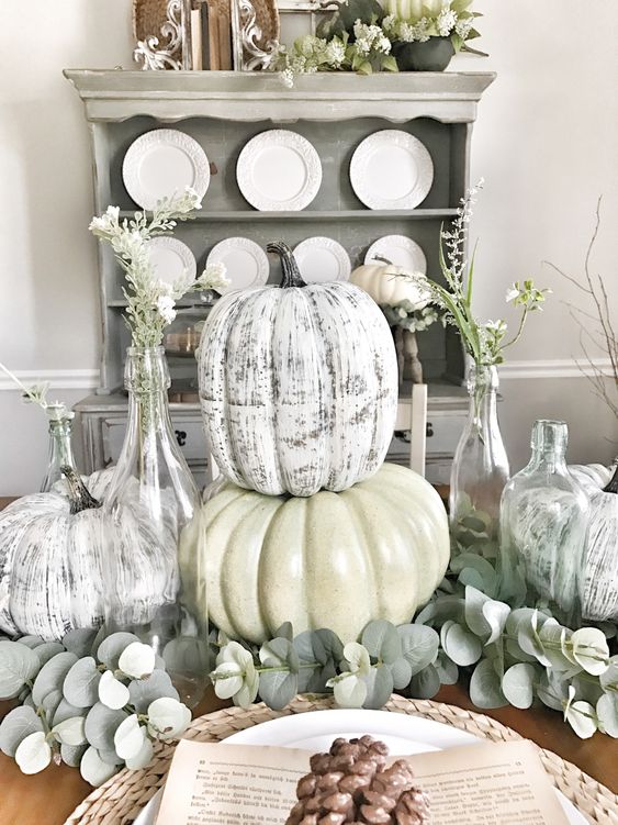 a vintage centerpiece of greenery, faux whitewashed pumpkins and some blooms in bottles for the fall