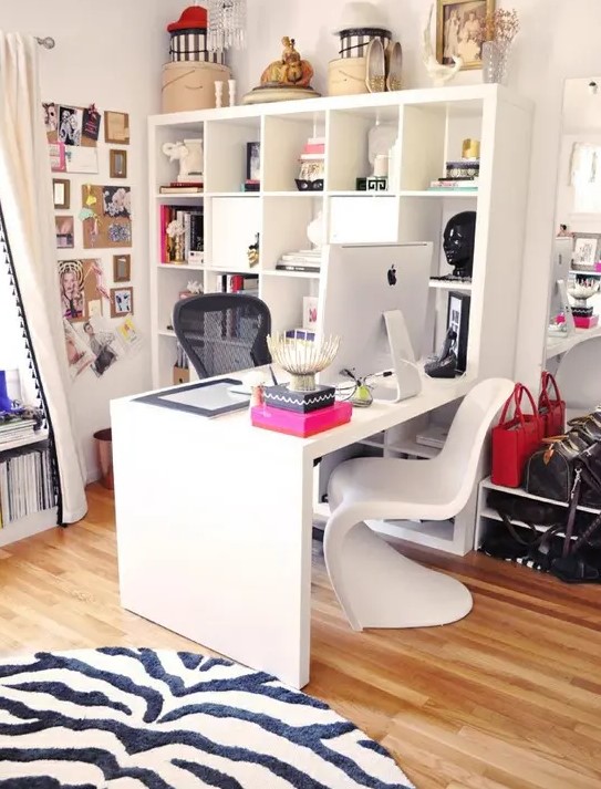 a vivacious feminine home office with an open storage unit, a desk, some chairs and a zebra rug plus bright pink touches
