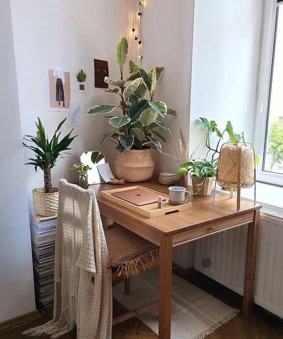 a welcoming boho nook with a desk, a wooden chair, potted plants, lights, a rattan lamp and baskets is very cozy and warming