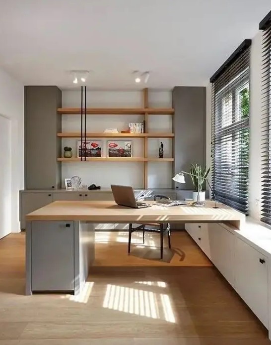 a welcoming contemporary home office with light grey storage units, stained shelves, a built-in matching desk and a black chair
