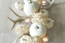 a white fall centerpiece of pumpkins, hydrangeas, antlers and candles is very pretty and elegant