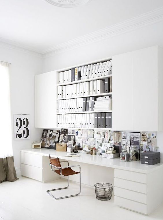 a white home office with large sleek and open cabinets, a large desk with drawers, a memo board is a very practical space