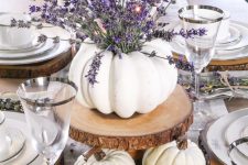 a white pumpkin vase with lavender on a wood slice, more white pumpkins under it for a fall table