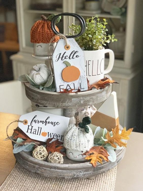 un support en bois blanchi à la chaux avec de fausses citrouilles, des feuilles d'automne, de la verdure dans une tasse, des étiquettes, des bonnets de citrouille en tricot un support en bois blanchi à la chaux avec de fausses citrouilles, des feuilles d'automne, de la verdure dans une tasse, des étiquettes, des bonnets de citrouille en tricot