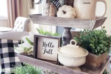 a wooden fall stand with potted greenery, white pumpkins, signs, jars and mugs plus plaid and striped textiles