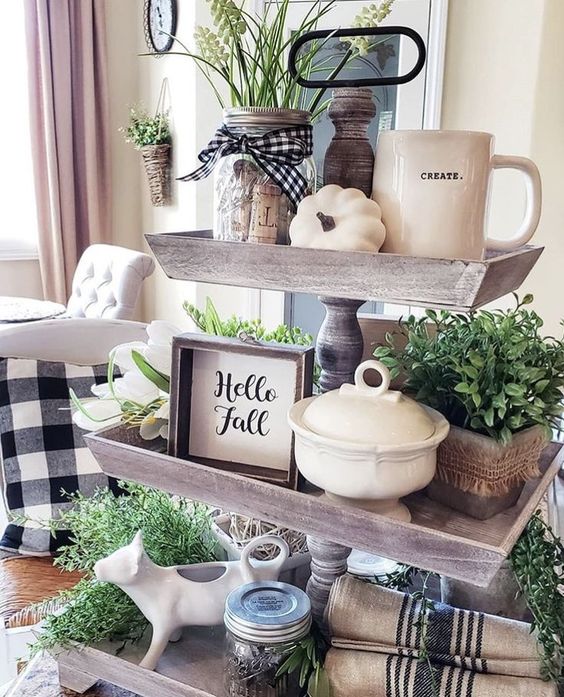 un support d'automne en bois avec de la verdure en pot, des citrouilles blanches, des panneaux, des bocaux et des tasses ainsi que des textiles à carreaux et à rayures un support d'automne en bois avec de la verdure en pot, des citrouilles blanches, des panneaux, des bocaux et des tasses ainsi que des textiles à carreaux et à rayures