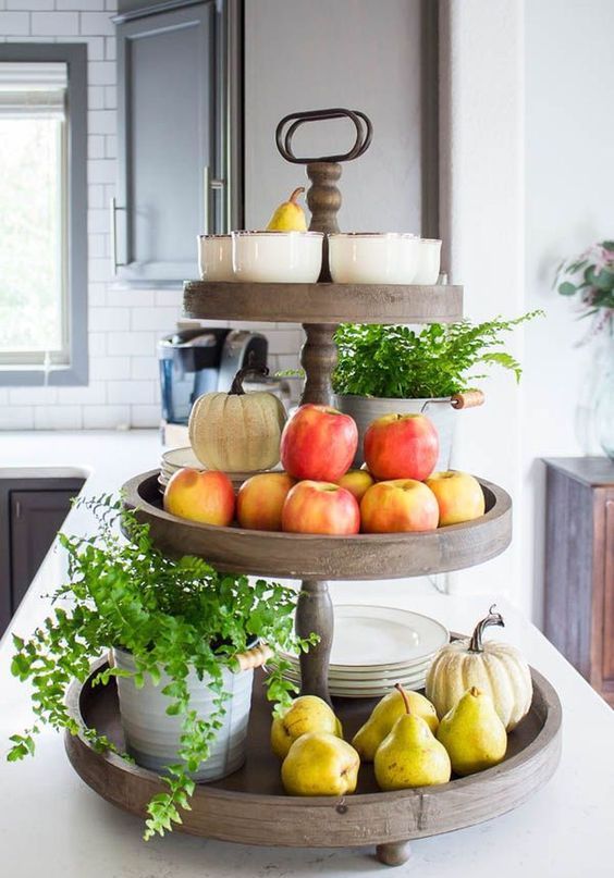 un support en bois avec de la verdure en pot, des pommes et des poires fraîches ainsi que des citrouilles et des assiettes un support en bois avec de la verdure en pot, des pommes et des poires fraîches ainsi que des citrouilles et des assiettes