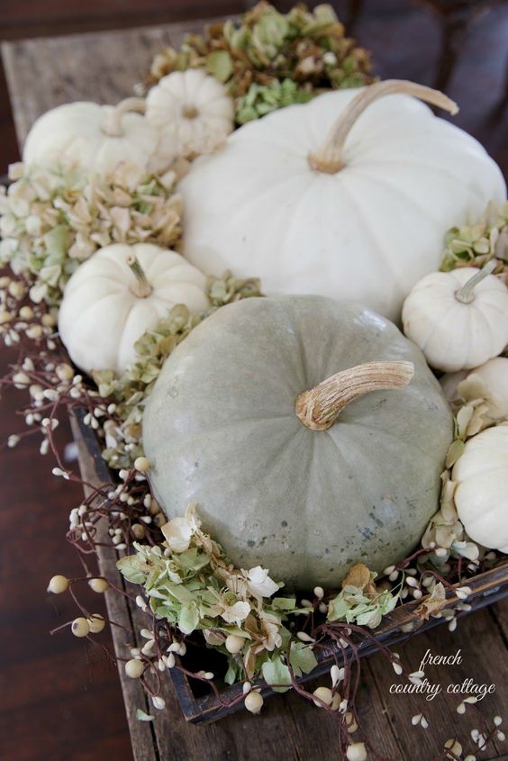 a wooden tray with white and chalky pumpkins, greenery and berries is a cool rustic fall centerpiece