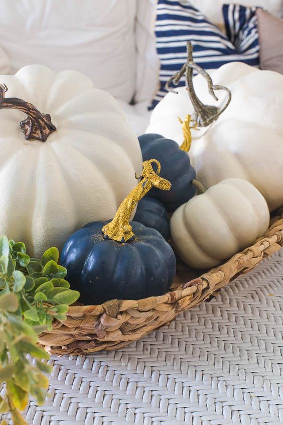 a woven basket with white and navy pumpkins and glitter touches for a glam and rustic fall centerpiece