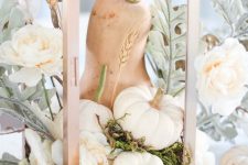 an airy fall centerpiece of a lantern with white pumpkins, a chalked gourd, pale greenery and white blooms and moss