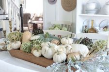 an all-natural fall centerpiece of a dough bowl, neutral pumpkins, green hydrangeas and pale greenery and wheat