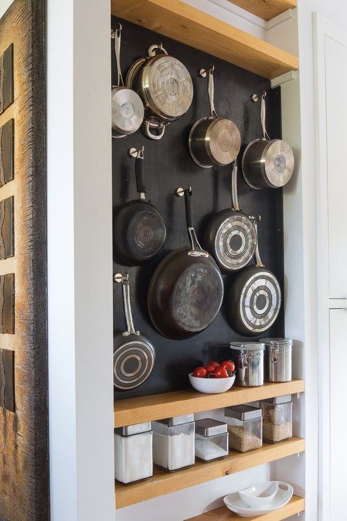 an open storage unit with open shelves and a chalkboard with hooks attached, which are ideal for hanging pots and pans