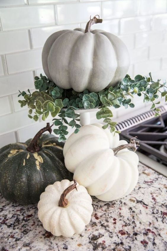 natural pumpkins including one on a stand with eucalyptus are neutral and cozy fall decor