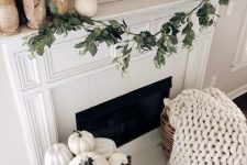 white fall fireplace styling with white pumpkins on wooden stands, white pumpkins on a vintage stand and a white chunky knit blanket
