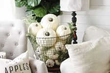 white pumpkins in a wire basket with greenery look harmonious in a neutral living room and add a fall touch to it