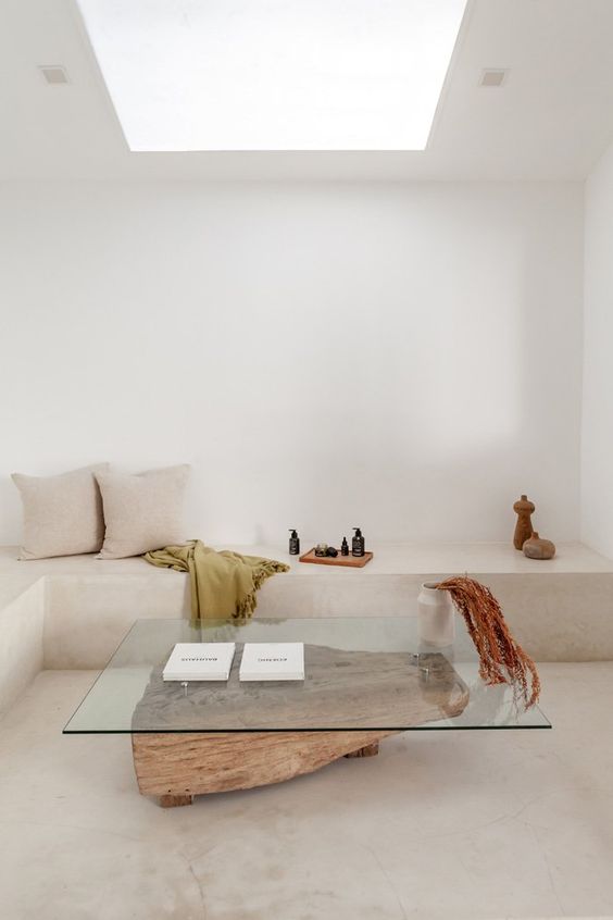 a bold modern coffee table of a piece of wood and a glass tabletop is a stylish addition to a minimalist living room