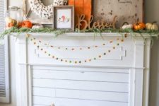 a bright rustic flal mantel with colorful pompom garlands, a crate with birch branches, lots of pumpkins, signs and a cotton wreath