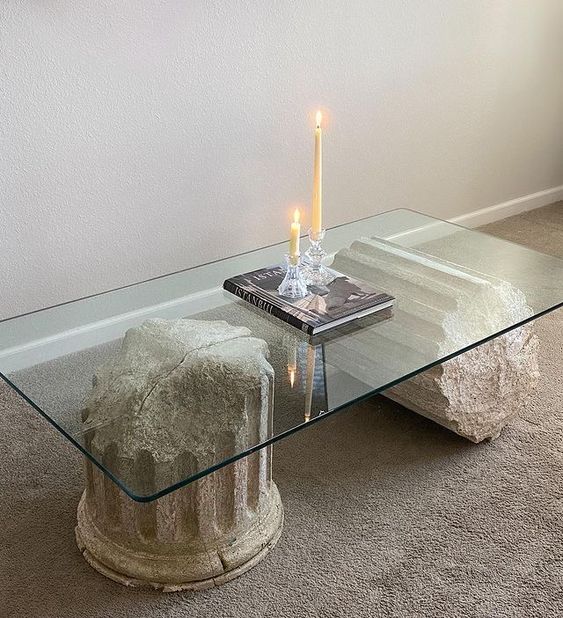 a catchy and bold coffee table of large pillar pieces and a glass tabletop is a cool idea for a modern space, it will add a sculptural touch