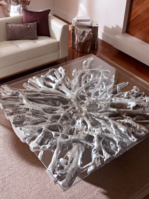 a catchy and chic coffee table of driftwood spray painted silver and a glass tabletop is a bold and catchy idea with a glam feel
