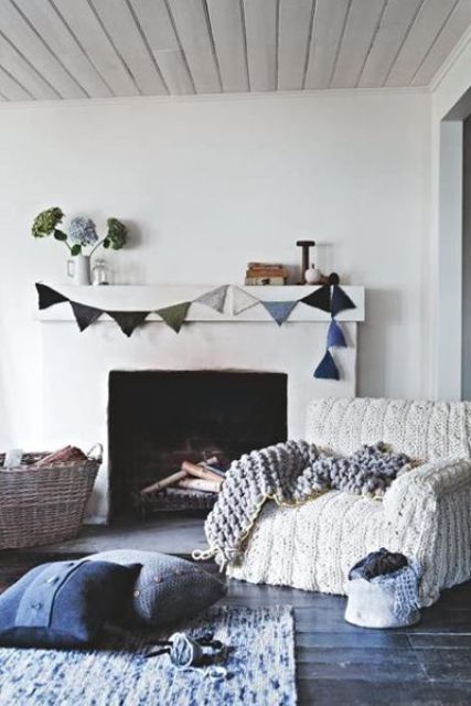 a chair with a white chunky knit cover, a chunky knit blanket and some pillows make the living room winter inspired