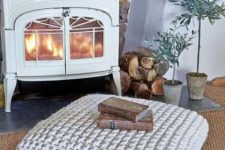a chunky knit square ottoman is a cozy and warming piece to place in front of your mantel