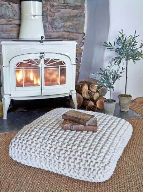 a chunky knit square ottoman is a cozy and warming piece to place in front of your mantel