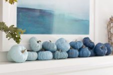 a coastal fall mantel decorated with faux veggies in various shades of blue to create an ombre effect