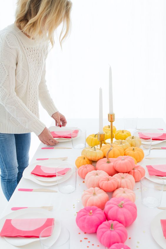 a contemporary fall tablescape in white and with colorful touches - a bold pumpkin table runner and pink napkins