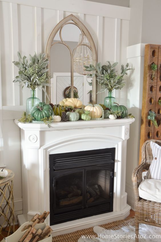 a fall mantel decorated with pinecones, faux pumpkins, pale greenery in tall bottles