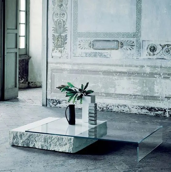 a gorgeous ultra-minimalist coffee table with a glass top and leg and a piece of rough stone as a support