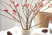a large branch-imitating vase with branches and berries is a simple contemproary centerpiece for the fall