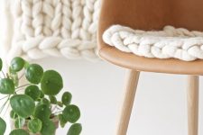 a leather chair with a white chunky knit cushion is much cozier and warmer than a usual one