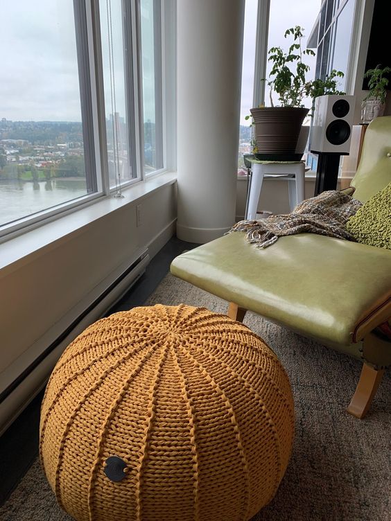 a leather lounger paired with an orange crochet pouf are a perfect nook for enjoying the views