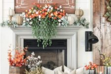 a lush fall mantel with pale greenery, faux pumpkins, gorgeous florals and cascading greenery, fall leaves and cotton in buckets and a fall sign
