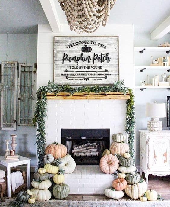 a modern farmhouse mantel with stacks of heirloom pumpkins, a greenery wreath and a large rustic sign