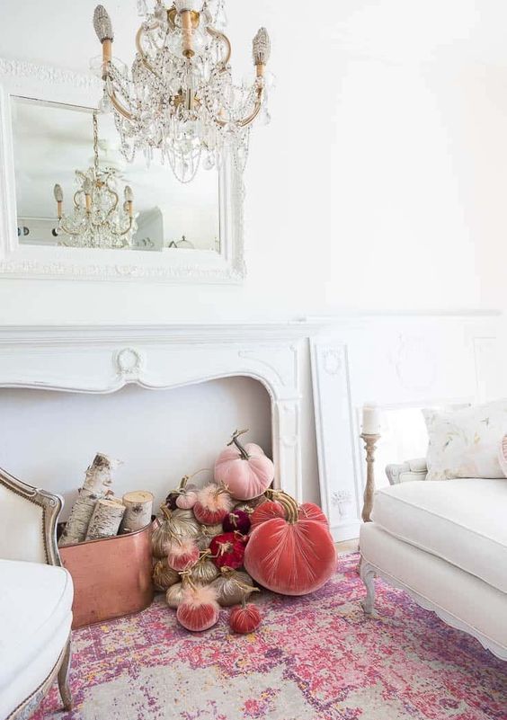 a refined and chic vintage mantel with a mirror in a gorgeous fram and a copper bucket with birch branches plus pink and coral velvet pumpkins