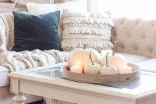 a round wooden tray with white pumpkins and candles is a simple yet very cute fall decoration in neutrals