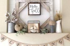 a rustic fall mantel with fabric pumpkins, wheat and cotton, a vintage book, a burlap banner and some greenery