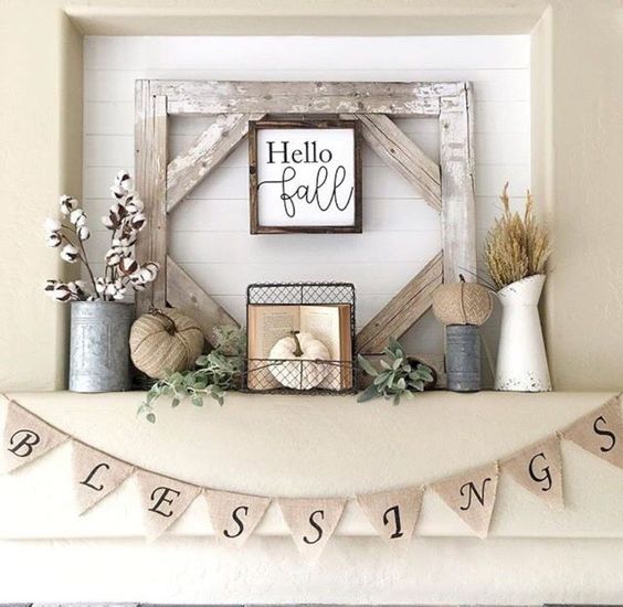 a rustic fall mantel with fabric pumpkins, wheat and cotton, a vintage book, a burlap banner and some greenery