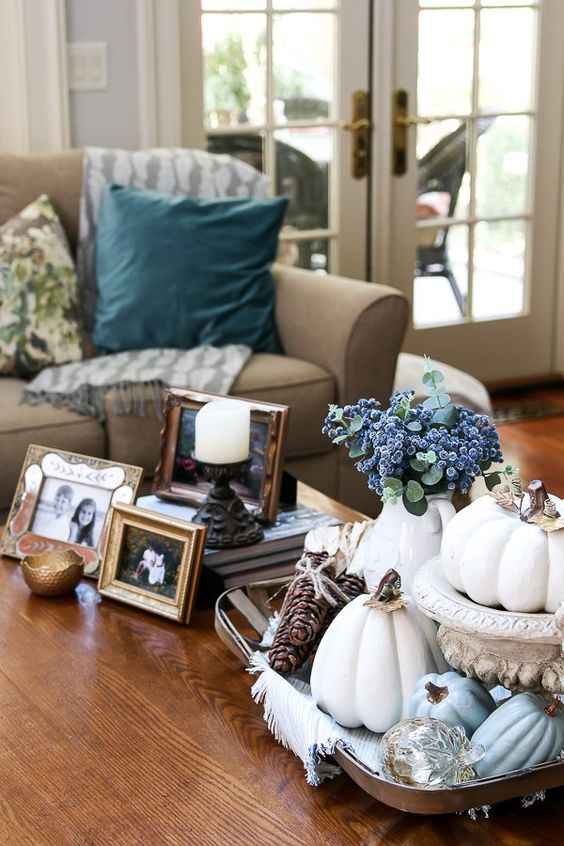 a silver tray with faux pumpkins painted whitte and powder blue, purple blooms and pinecones