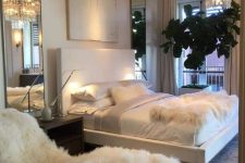 a sophisticated bedroom with a white faux fur lounger and a matching throw on the bed is all glam and chic