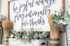 a stylish modern farmhouse mantel with wheat arrangements, a large sign, a whitewashed box with pale greenery and berries